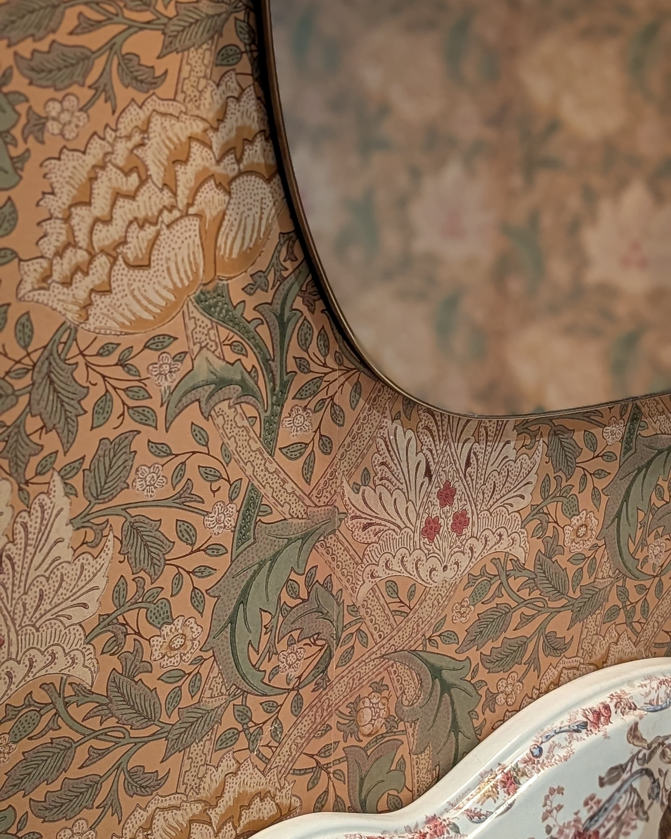Floral wallpaper reflected in a round mirror in an Amsterdam cafe